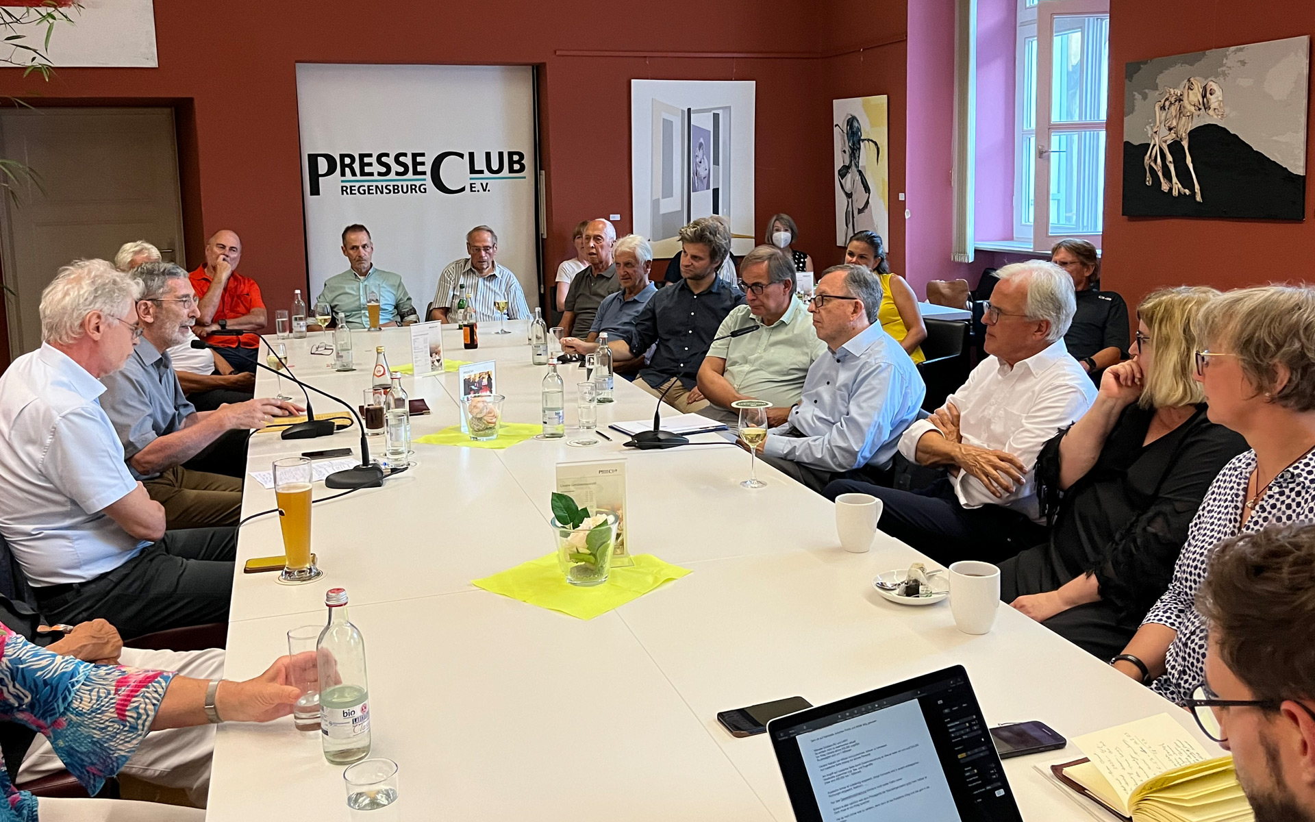 Die Mitglieder sitzen um eien Konferenztisch